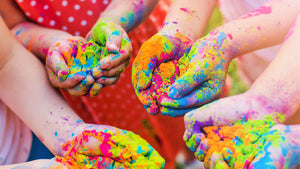 Des enfants lors d'un événement dans une garderie avec des poudres de couleur dans les mains.